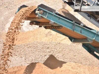 Conveyor belt tension system unloading sand and aggregate onto stockpiles during quarry site operations