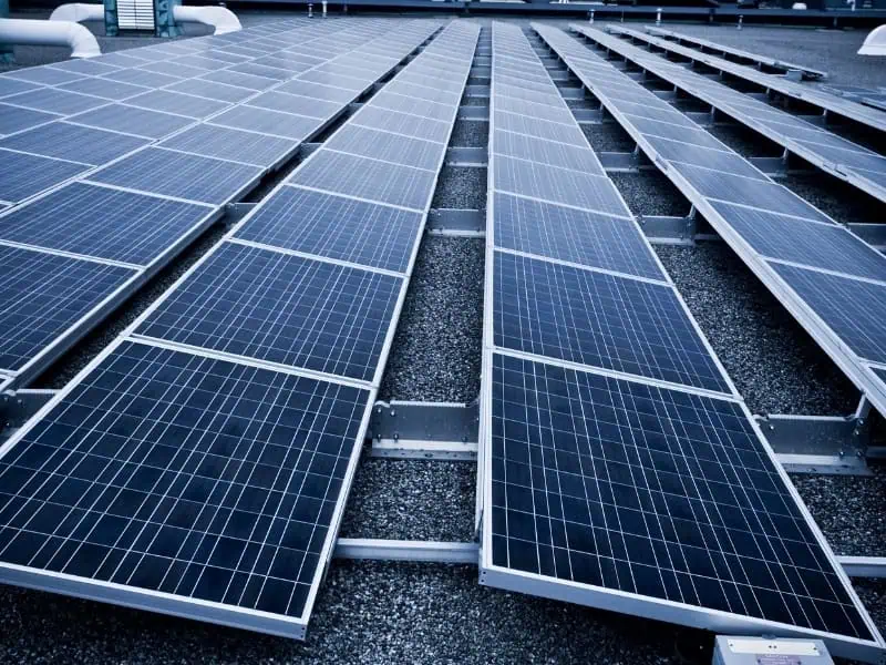 Solar Panel Lifter Hire for large flat-roof solar array installation with multiple mounted panels.