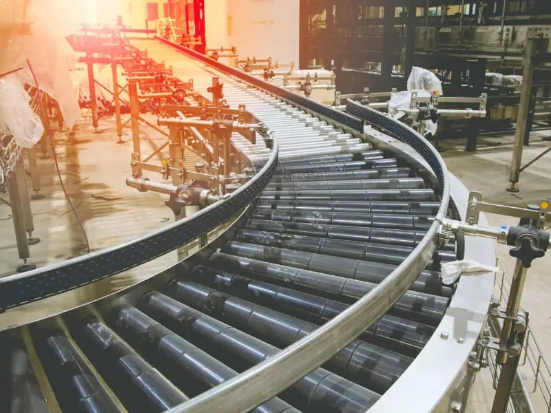 Curved Roller Conveyor Types with black rollers and guide rails in an industrial setting.