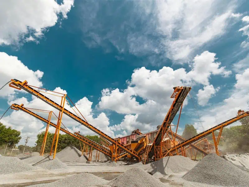 construction conveyor belt network at quarry moving crushed stone between stockpiles with orange frames under cloudy sky