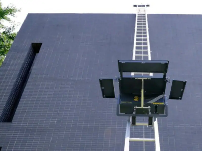 ladder elevator platform ascending a tall facade with open side flaps ready for loading