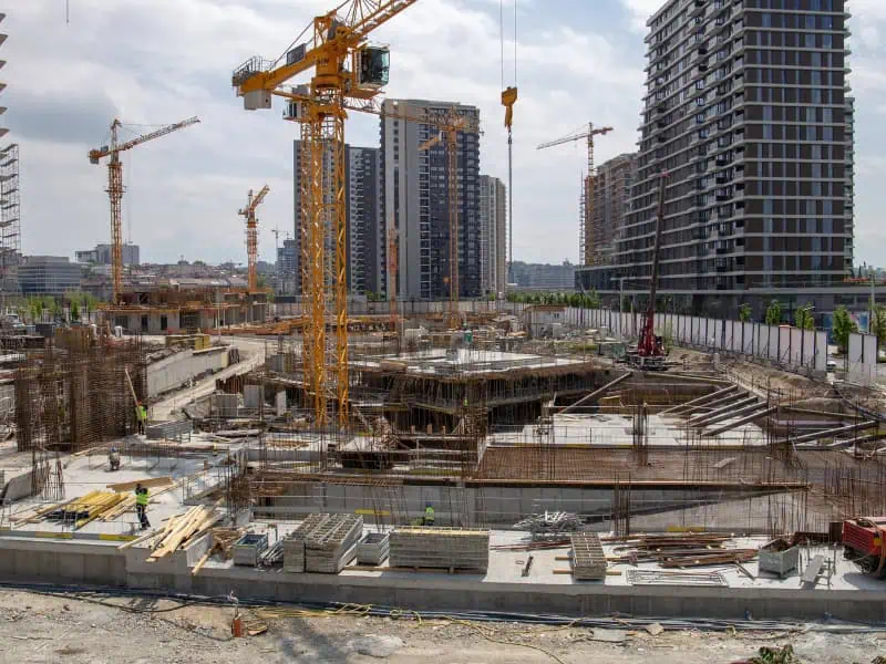 Construction Material Lifts used on large building site with cranes and workers handling materials.