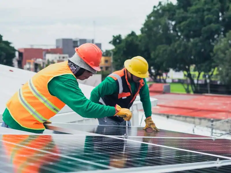 Solar Panel Lift Rental supports workers installing panels on rooftop project.