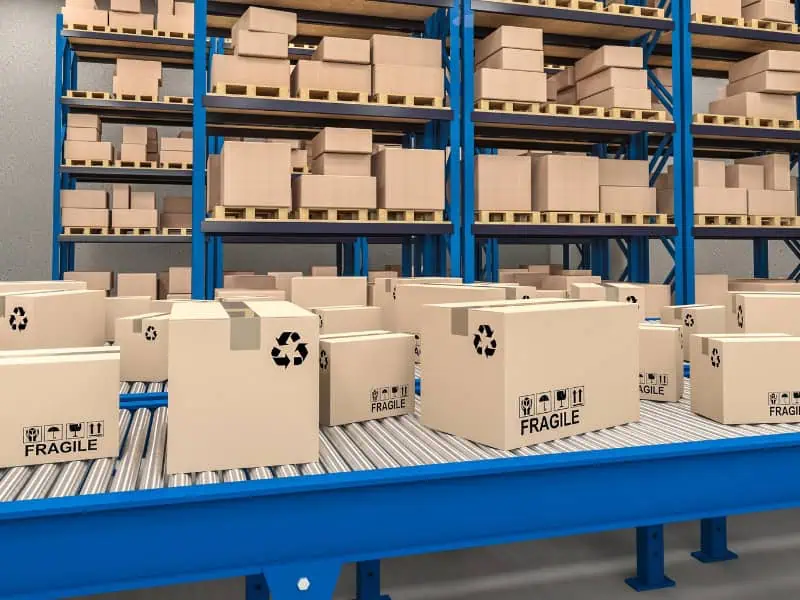 Warehouse Conveyor carrying fragile labelled boxes near storage racks.